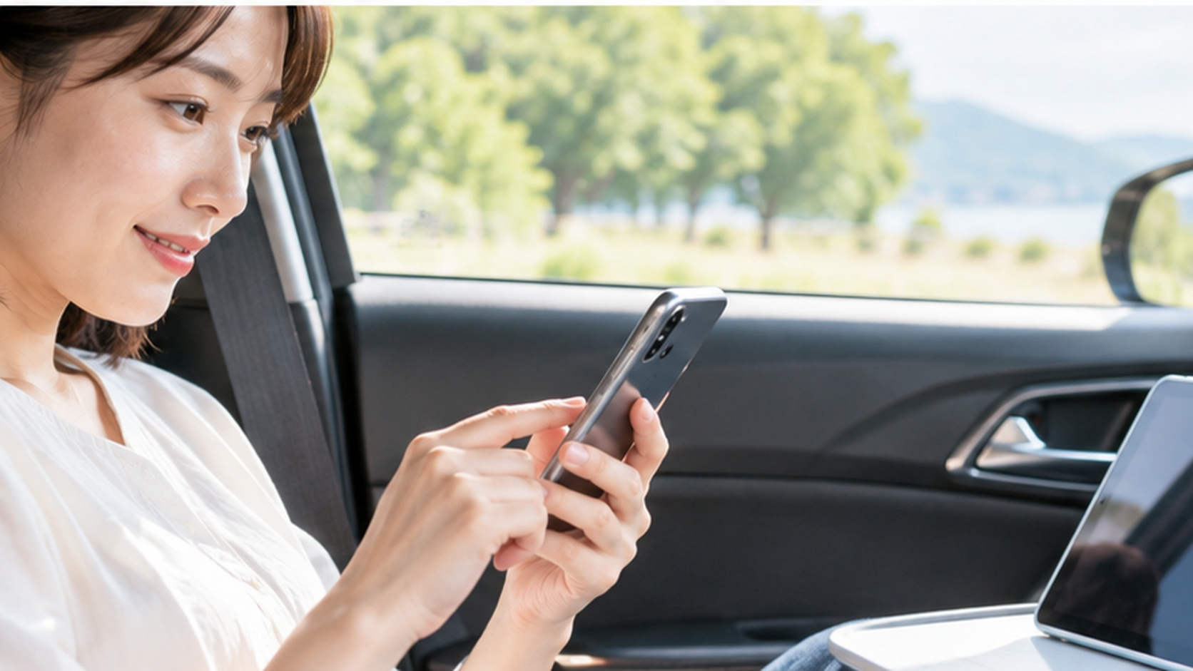 停車中の車内でスマホを操作し、隣のタブレットに通信を共有する準備をする様子