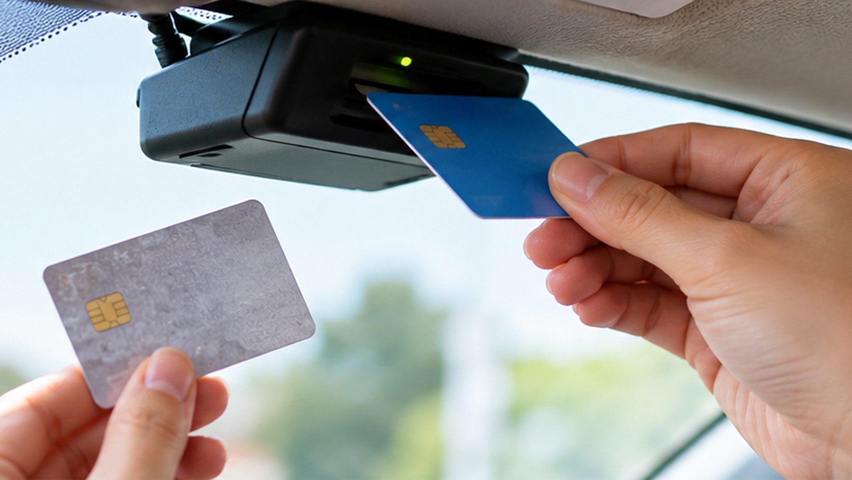 車内で古い銀色のETCカードを手元に持ち、新しい青色のカードを車載器に差し込んで交換する手元
